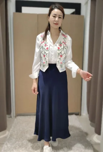 mujer con camisa blanca, chaleco y falda azul