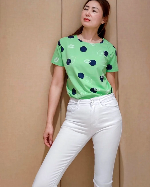 mujer posando con camiseta estampada y pantalón blanco